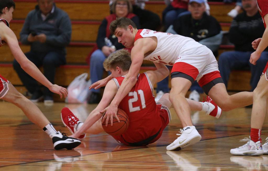 Marysville Pilchucks Aaron Kalab leaps over Stanwoods Dom Angelshaug for the ball as they scramble on the floor. Marysville Pilchuck beat Stanwood 76-31 in a basketball game Monday, Feb. 10, 2020 in Marysville. (Andy Bronson / The Herald)