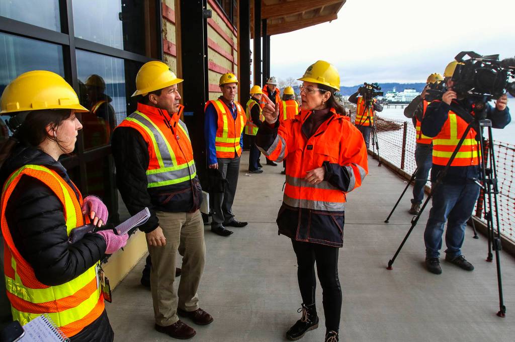 On the broad walkway facing the water WSDOT spokesperson Diane Rhodes (center) talks with reporters and photojournalists visiting the new passenger terminal under construction at Mukilteo, Thursday. (Dan Bates / The Herald)