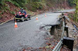 A resident uses an ATV to navigate the washed out and crumbling road bed of 260th Ave NE leading to Skyview Estate in Monroe on February 13, 2020. (Kevin Clark / The Herald)