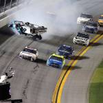 Denny Hamlin (front left) passes Ryan Blaney (front right) on the way to the finish line to win the Daytona 500 while Ryan Newmans No. 6 car flips over the field Monday at Daytona International Speedway in Daytona Beach, Florida. (AP Photo/David Graham)