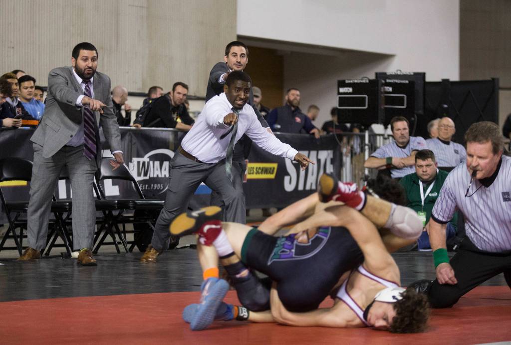 Edmonds-Woodway coaches cheer on Warriors sophomore Alex Rapelje (top) in his 138-pound title match against Prairies Jacon Wilcox during Mat Classic XXXII in the Tacoma Dome on Saturday. (Andy Bronson / The Herald)