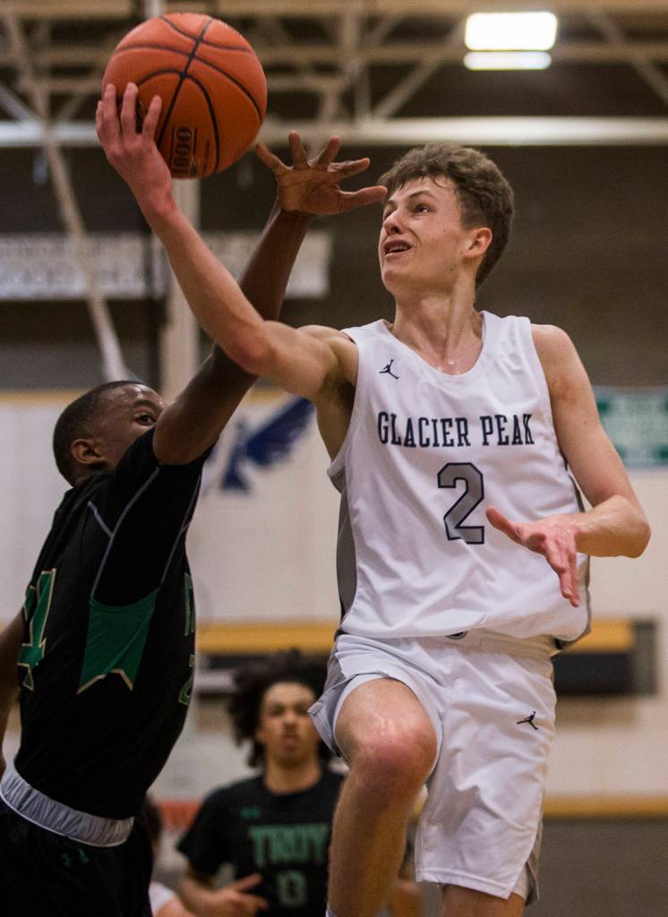 Glacier Peaks Caleb Lee (right) lays up the ball while being guarded by Auburns DaeKwon Watson during a 4A state regional game on Saturday at Shorewood High School in Shoreline. (Olivia Vanni / The Herald)
