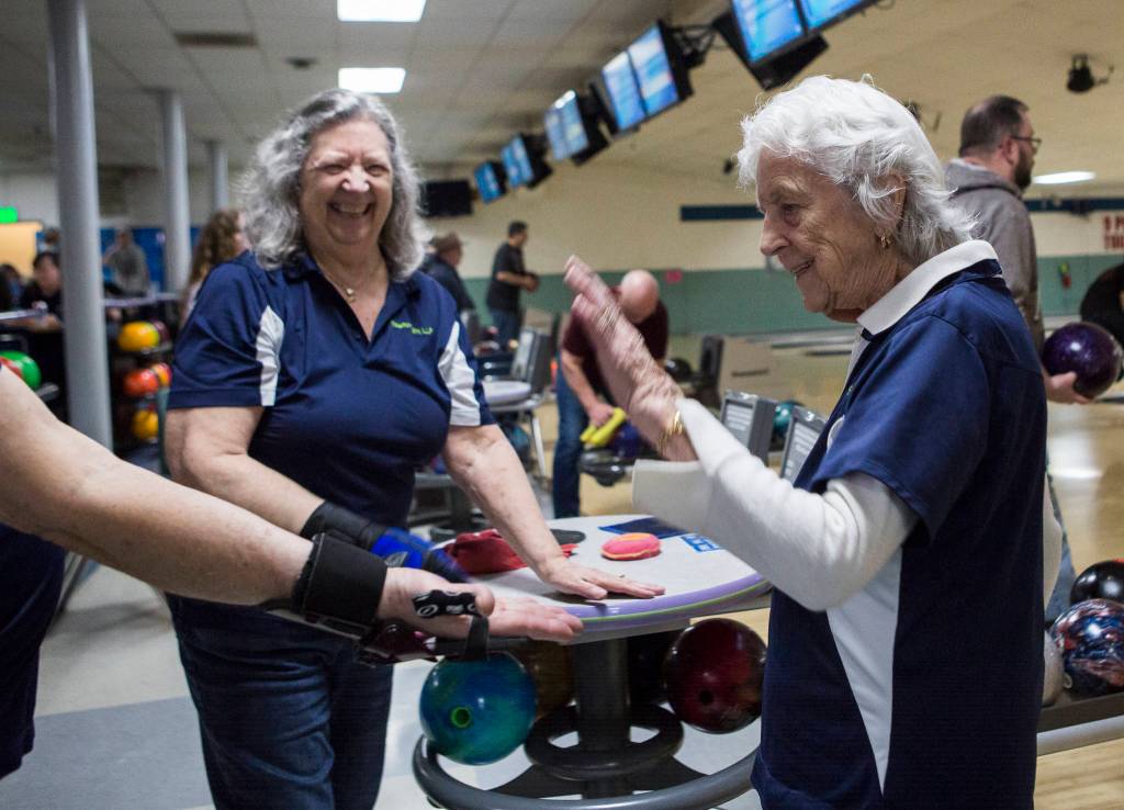 Carol Perry high fives her teammates after getting a strike during league bowling. (Olivia Vanni / The Herald)