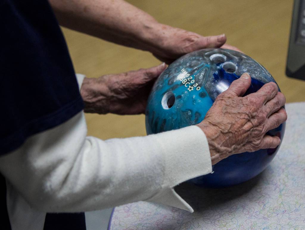 Carol Perry holds her ball as she waits for her turn during league bowling. (Olivia Vanni / The Herald)