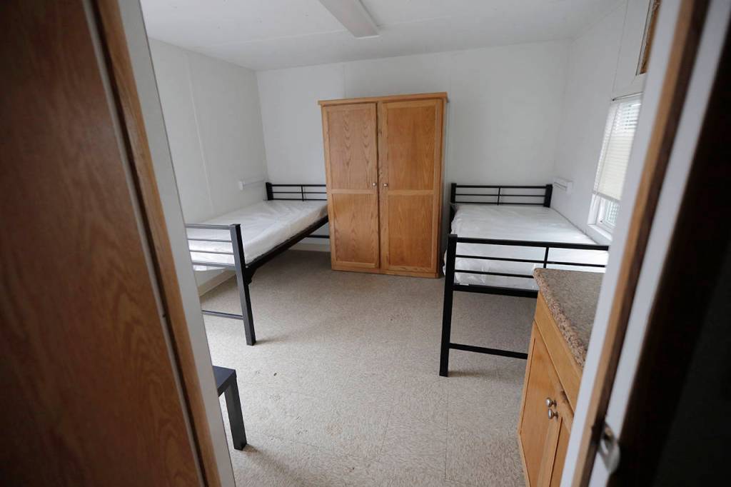 Barbara Ramey (third from left), deputy communications manager for the King Co. Dept. of Executive Services, briefs reporters Tuesday at the site in South Seattle where King County will be placing several temporary housing units like the one shown behind her to house patients undergoing treatment and isolation in response to the COVID-19 coronavirus. (AP Photo/Ted S. Warren)