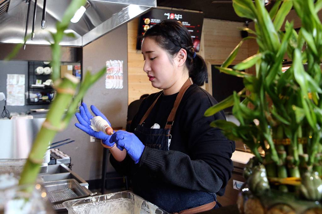 Seoul Hotdog co-owner Aram Han makes a Korean corn dog at the new shop in Lynnwood. (Kevin Clark / The Herald)