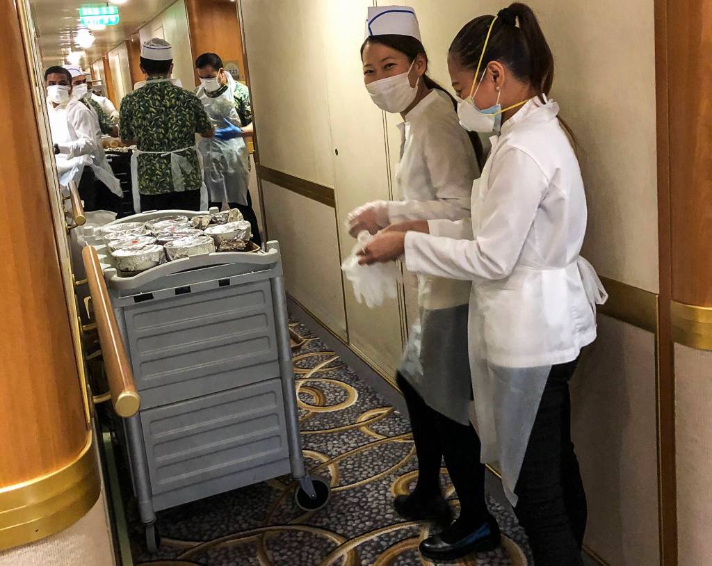 Diamond Princess cruise crew members wear masks as they serve meals to passengers quarantined in their rooms on Feb. 13. (Susan Anabel)