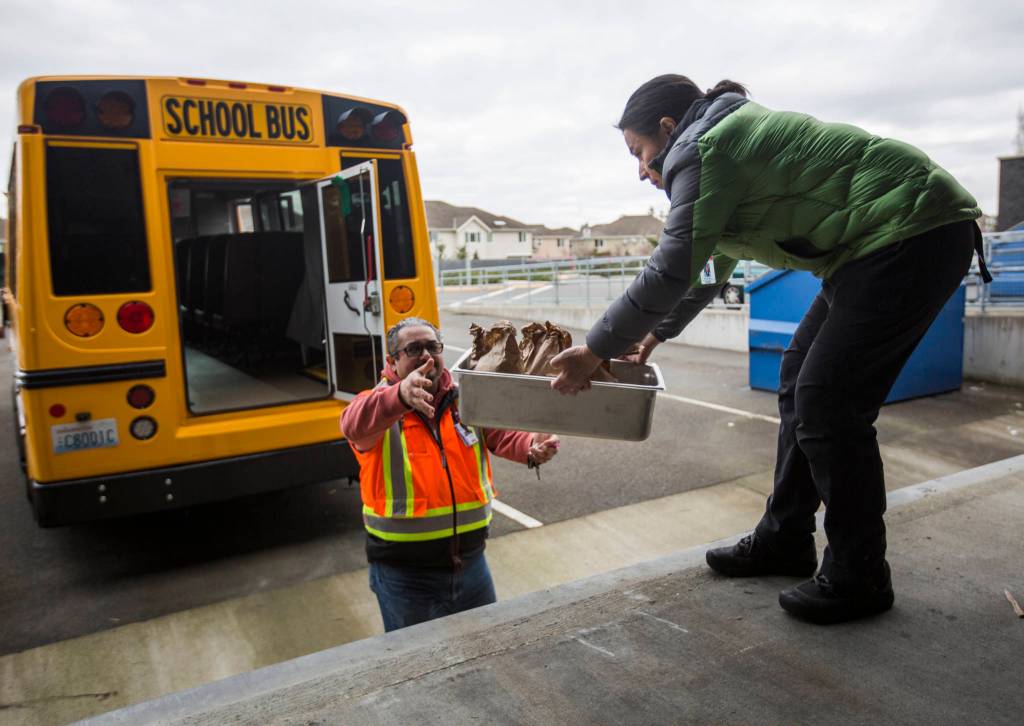 Ileana Koons, right, hands Jorge Rodriguez meals to be delivered to students on Thursday in Bothell. (Olivia Vanni / The Herald)