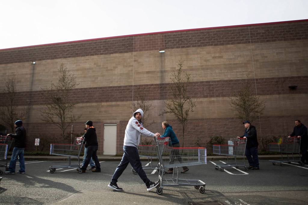 People begin lining up at Costco where the line wrapped around the back of the building on Tuesday in Everett. (Olivia Vanni / The Herald)