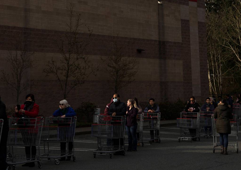 A man stands in line with a mask on Tuesday in Everett. (Olivia Vanni / The Herald)