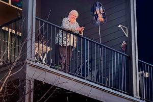 Carolyn Ross, on the balcony of her apartment at Arlingtons Olympic Place, is happily surprised on her 96th birthday Monday. Unable to visit the senior community due to coronavirus precautions, her children and their spouses sang Happy Birthday from outside. (Vanessa Ross photo)