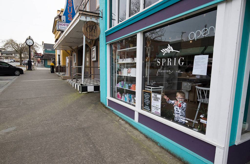 Elliott West, 2, peers out at a nearly empty First Street in Snohomish on Tuesday. He was hanging out with his mom as she filled orders at Sprig Flower Co. (Andy Bronson / The Herald)                                 Elliott West, 2, peers out at a nearly empty First Street on Tuesday, March 17, 2020 in Snohomish, Wa. West was hanging out with his mom as she fills packing orders at Sprig Flower Co. (Andy Bronson / The Herald)
