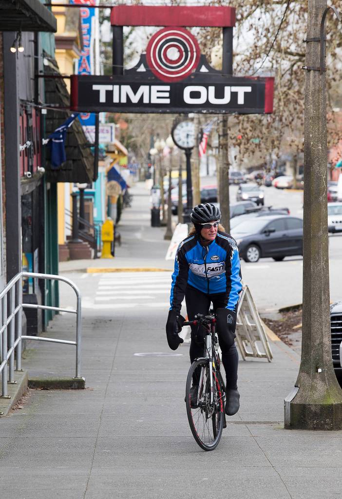 With public bathrooms closed, biker Lisa Worthington heads back out to finish her ride on First Street in Snohomish on Tuesday after finding a business that let her stop in. (Andy Bronson / The Herald)