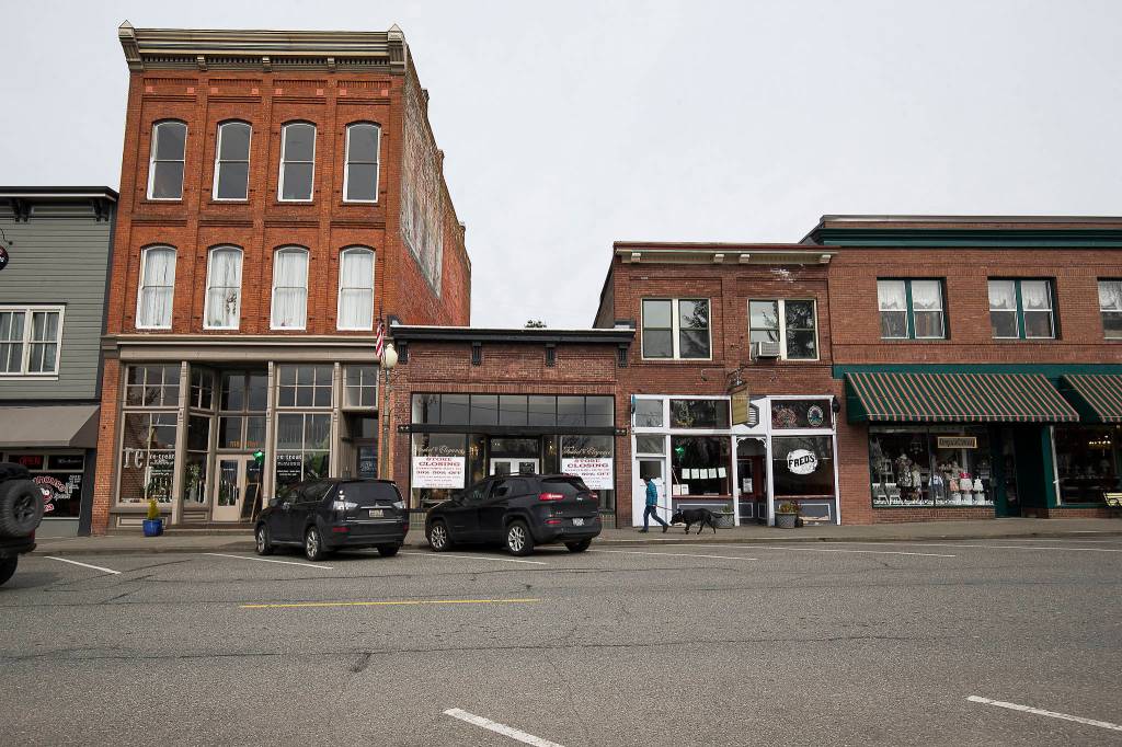 A pedestrian walks along a nearly empty First Street in Snohomish on Tuesday. On a normal day, parking is hard to find and pedestrians are many on the street of antique shops and restaurants. (Andy Bronson / The Herald)