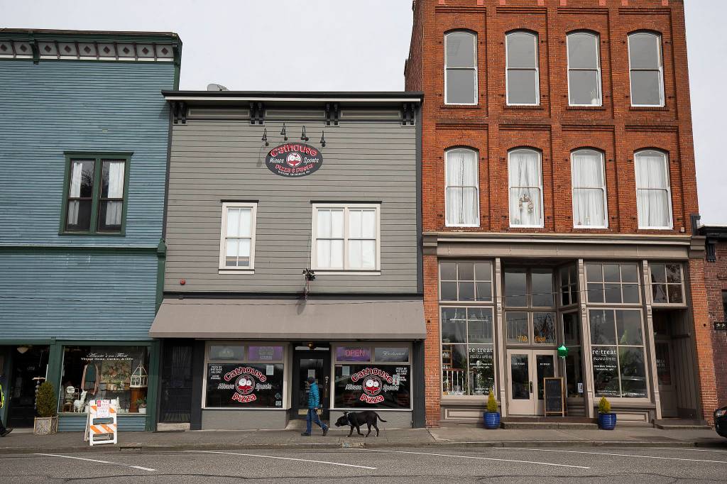 A pedestrian walks with her dog down a nearly empty First Street in Snohomish on Tuesday. (Andy Bronson / The Herald)