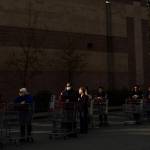 A man with a mask stands in line with hundreds of other shoppers waiting for Costco to open on Tuesday in Everett. (Olivia Vanni / The Herald)