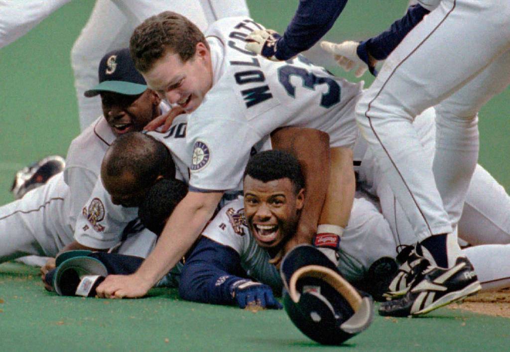 The Mariners Ken Griffey Jr. smiles from beneath a pile of teammates who mobbed him after he scored the winning run on a double by Edgar Martinez in the bottom of the 11th inning of Game 5 of the American League Division Series against the New York Yankees in 1995 in Seattle. (AP Photo/Elaine Thompson)