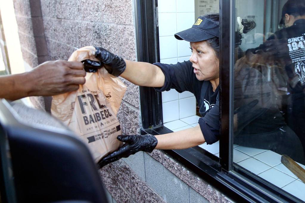 Vivian Martinez hands over an order via the drive-thru at Dickeys Barbecue Pit in Everett. (Kevin Clark / The Herald)