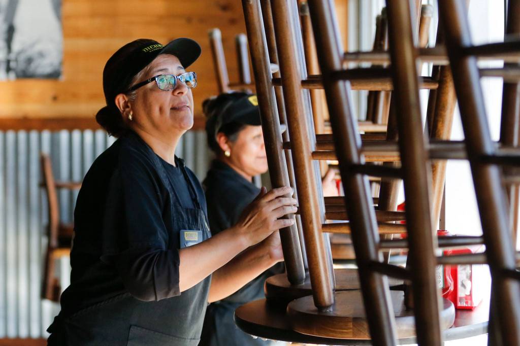 Justina Dios stacks stools at Dickeys in Everett on March 20. (Kevin Clark / The Herald)