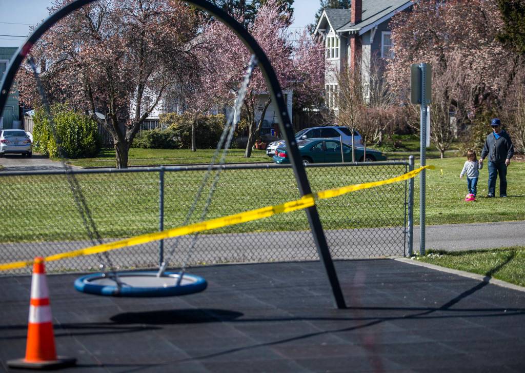 Liam Fitzgerald and his daughter Lillian, 3, walk past the closed Northwest Everett Neighborhood Park on Friday, March 20, 2020 in Everett, Wa. (Olivia Vanni / The Herald)