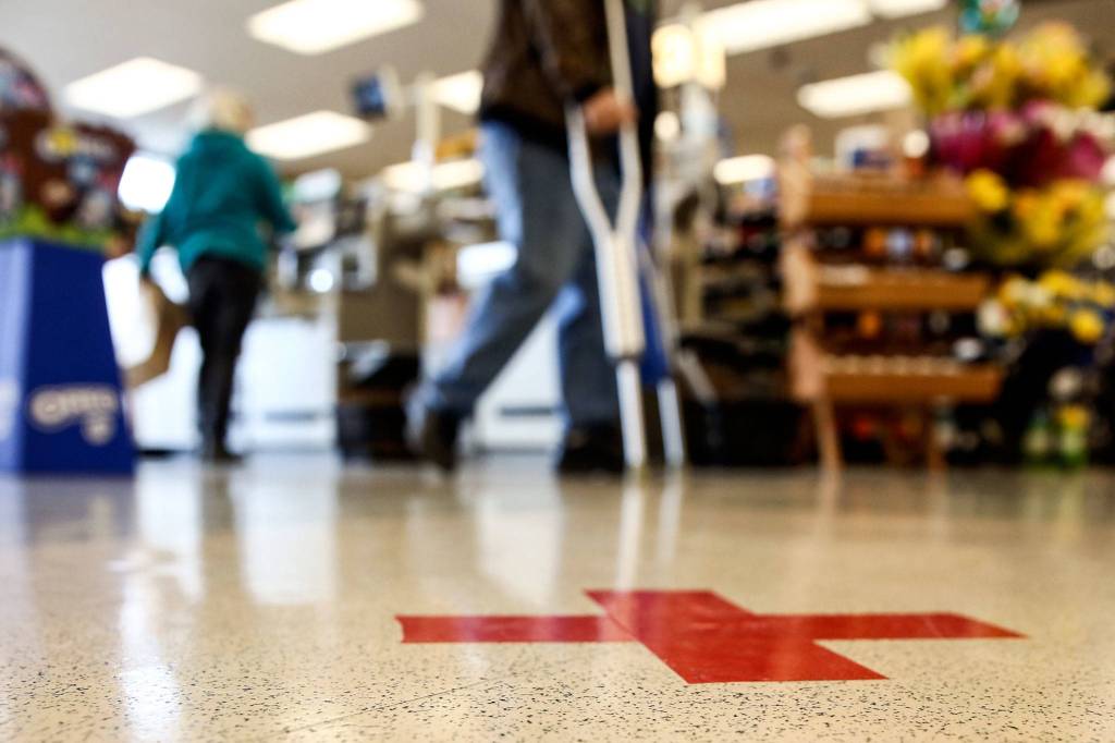 Spaced markers dot the floor Wednesday afternoon at QFC in Everett. (Kevin Clark / The Herald)
