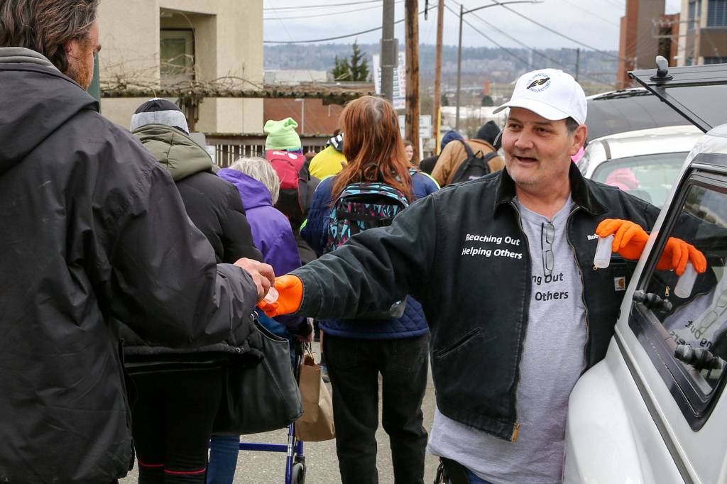 Robert Smiley of The Hand Up Project hands out hand sanitizer in downtown Everett Thursday afternoon. (Kevin Clark / The Herald)