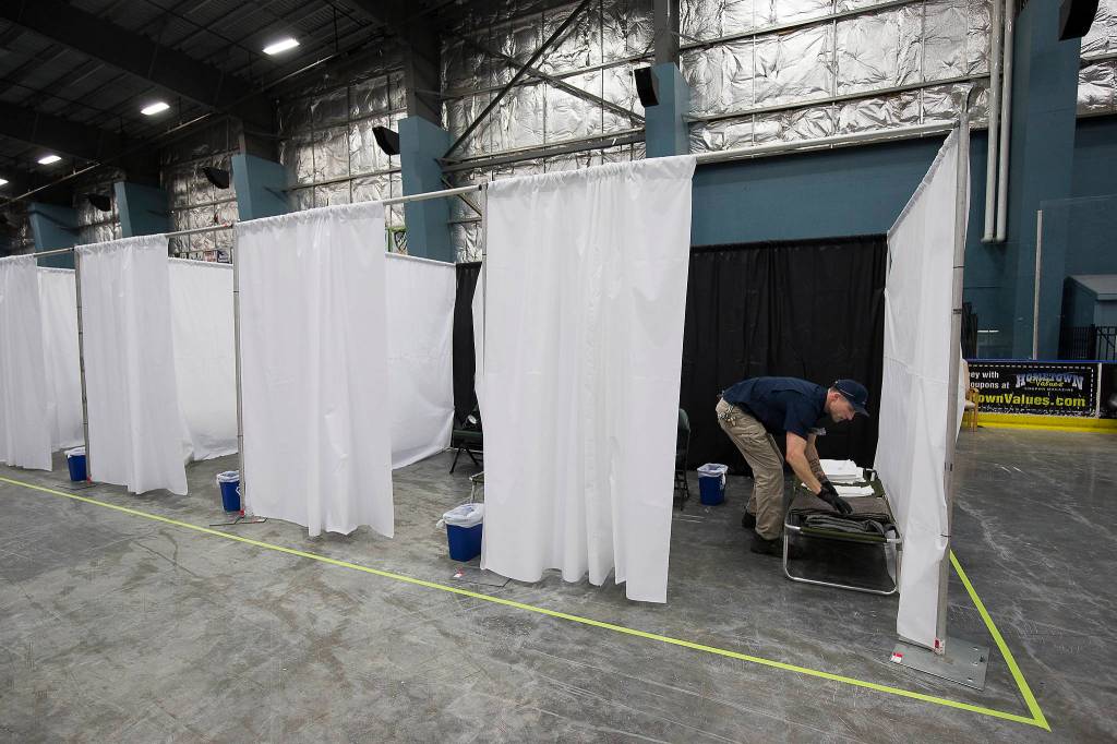 Snohomish County facilities employee Mac Bierman sets up the smaller community ice rink as an isolation site at Angel of the winds Arena on Tuesday. (Andy Bronson / The Herald)