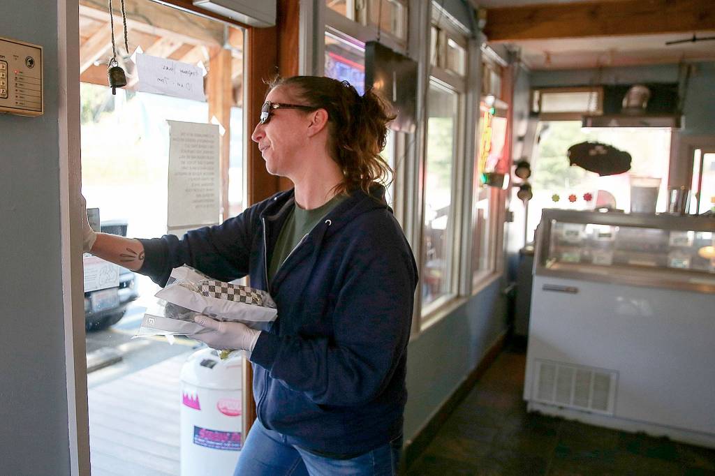 Dee Hatch delivers a food order to a waiting customer at Sky Deli. (Kevin Clark / The Herald)