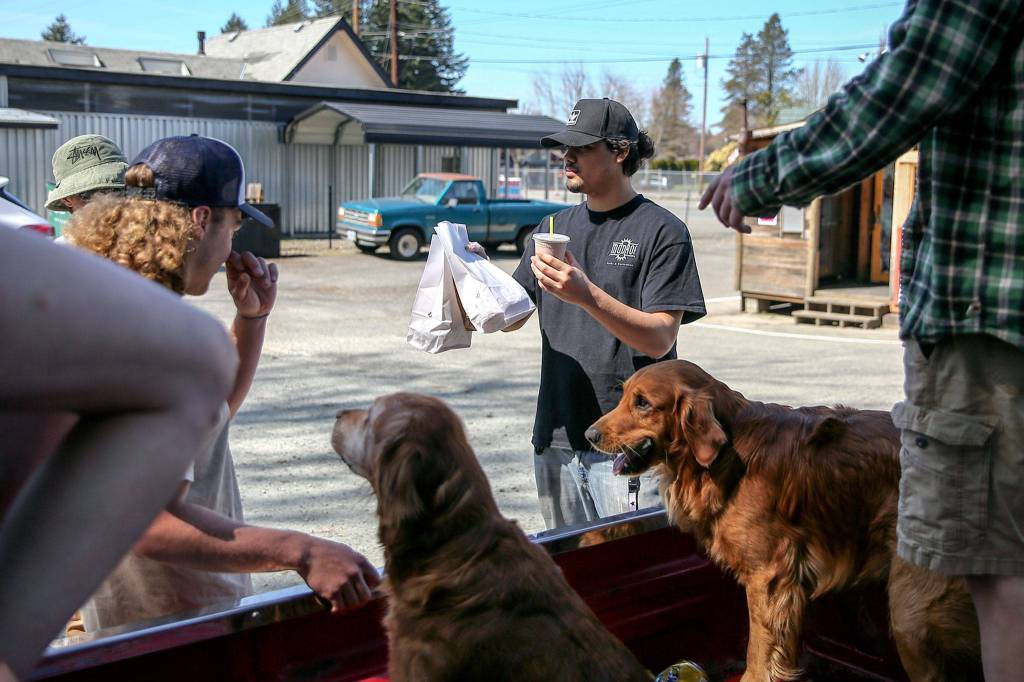 Rodger Pestana carries out an order at Vicks Burger Shack in Sultan. He says business is booming during the shutdown. (Kevin Clark / The Herald)
