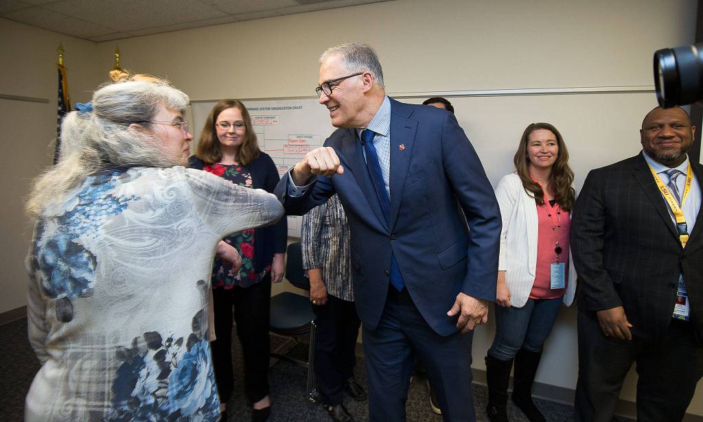 Governor Jay Inslee bumps elbows with staff before a group photo at the Snohomish Health Districts Incident Command Center on March 6 in Everett. (Andy Bronson / The Herald)