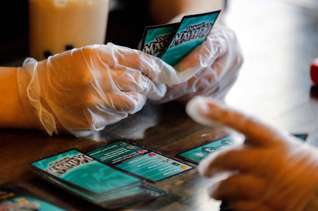 Customers wear gloves while playing a game at Around the Table Game Pub in Lynnwood on March 15. (Kevin Clark / The Herald)