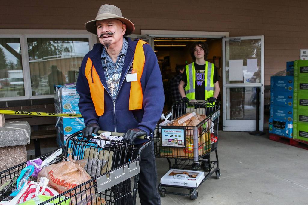Reggie Ramey Sr. (left) and Leif Winter await customers at Marysville Community Food Bank on March 24. (Kevin Clark / The Herald)