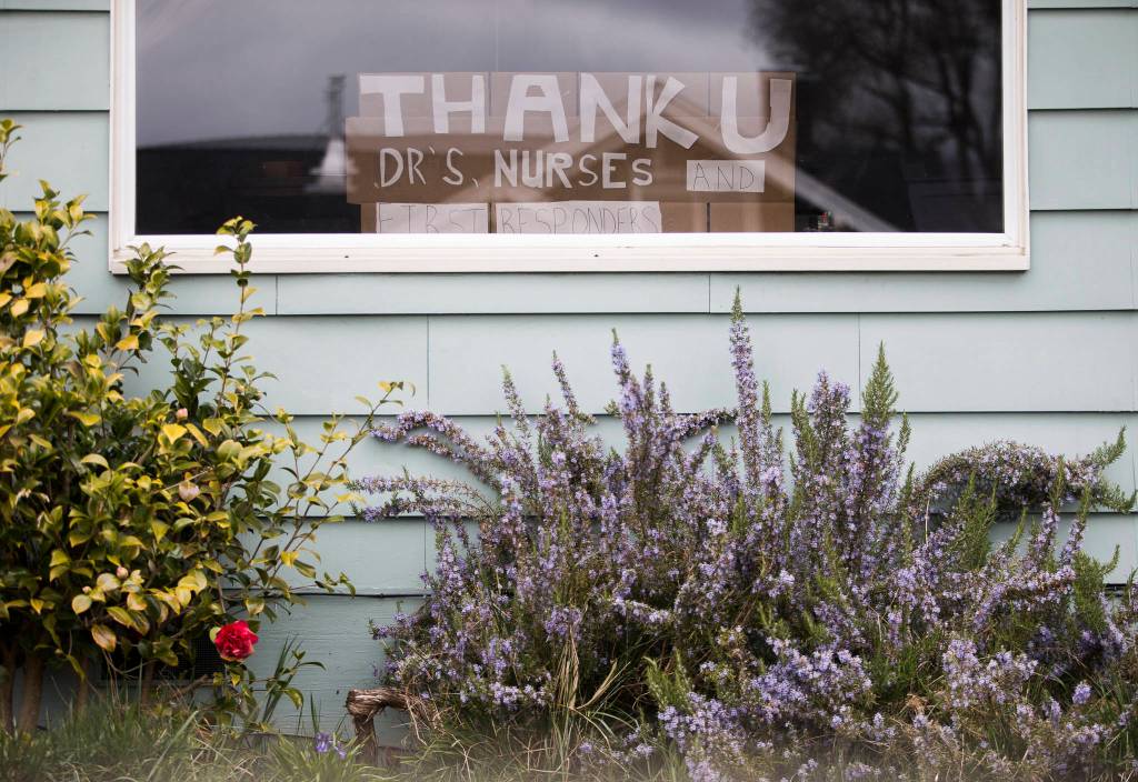 A sign with the phrase, thank u drs nurses and first responders sits on display in a window of a home along 15th Street on Friday in Everett. (Olivia Vanni / The Herald)