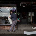 Ethan Spain puts a temporary vinyl on the front window of Piccadilly with the phrase, eat, drink and be happy Friday in Snohomish. (Olivia Vanni / The Herald)