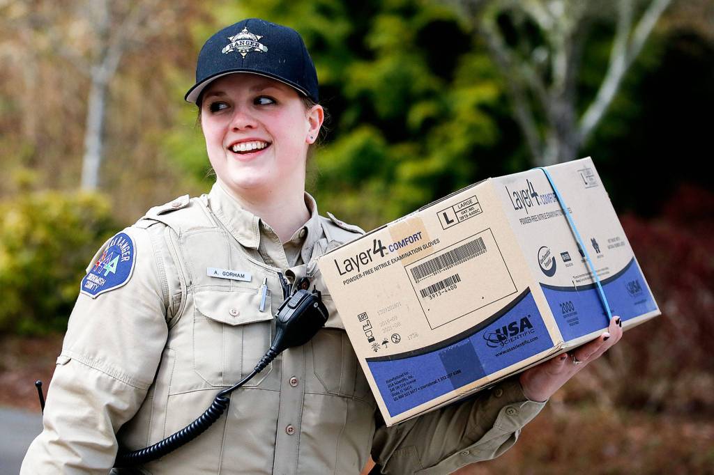 Alyssa Gorman, Snohomish County Park Ranger, carries donated personal protection equipment Wednesday at the Willis Tucker Park administration building in Snohomish. (Kevin Clark / The Herald)
