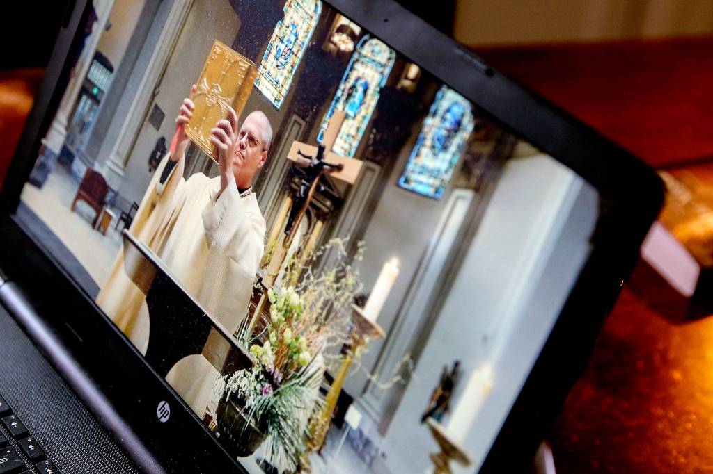 The Mass of the Lords Supper Livestream from St. James Cathedral at the home of Jeffrey Morrnis in Seattle on Thursday. (Kevin Clark / The Herald)