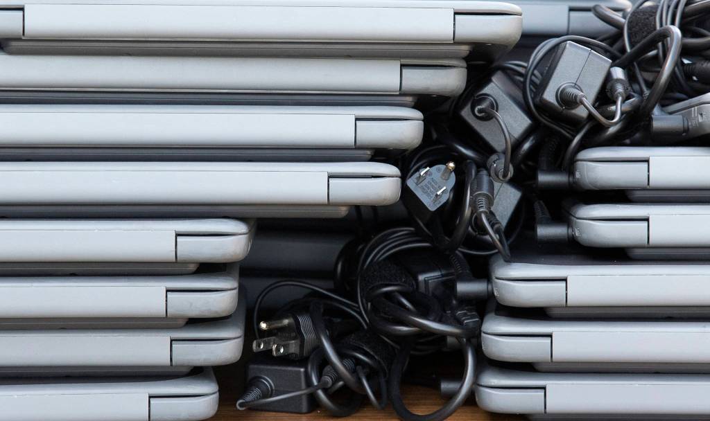 Chromebooks are stacked as staff at Frank Wagoner Elementary School help students set up computers for online learning. Gov. Jay Inslee announced Monday that schools statewide would stay closed through the end of the academic year. (Andy Bronson / The Herald)