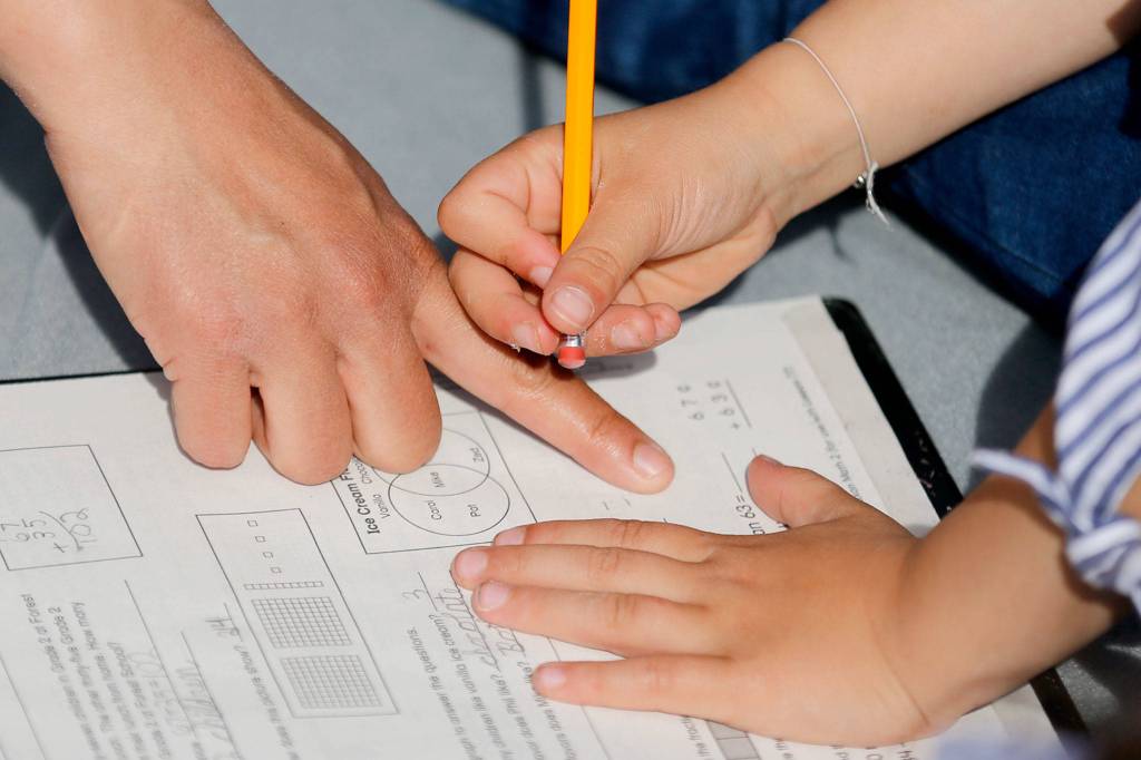 The Bone Family work to complete an assignment Friday morning at their home in Everett on April 17, 2020. (Kevin Clark / The Herald)