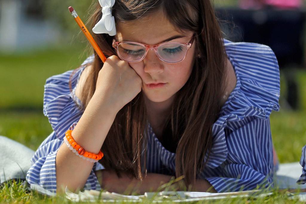 Paige Bone, 7, works through an assignment Friday morning at their home in Everett on April 17, 2020. (Kevin Clark / The Herald)