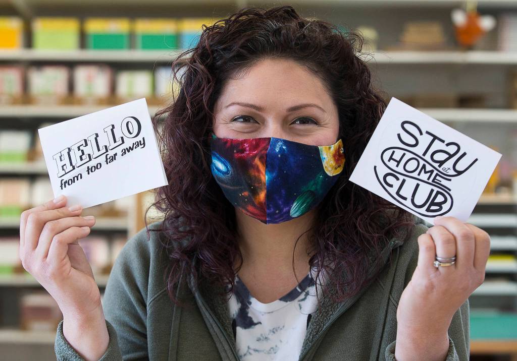 Cat Snapp shows off two of her downloadable cards in her studio in Everett. The cards print in black and white, so the customer can color them in themselves. (Andy Bronson / The Herald)