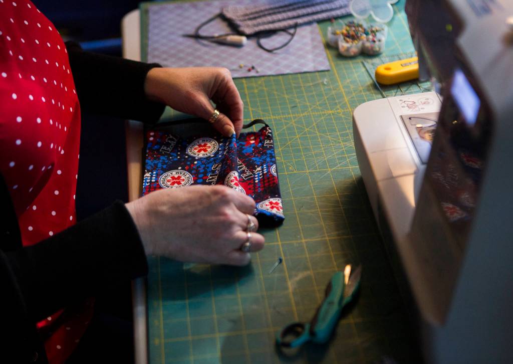 Nikki Speaks folds emergency response themed fabric for a mask on April 10 in Woodinville. (Olivia Vanni / The Herald)