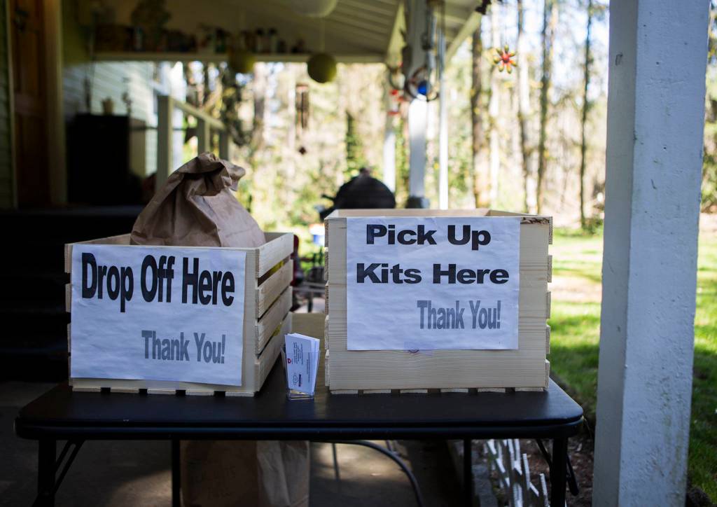 Two bins, one for drop off of finished masks, another for picking up mask kits, sit near the entrance of Nikki Speaks home on April 10 in Woodinville. (Olivia Vanni / The Herald)
