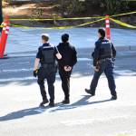 Police escort a man out of an apartment building at the corner of Rucker and Everett avenues after a shooting in the area Thursday afternoon. (Sue Misao / The Herald)