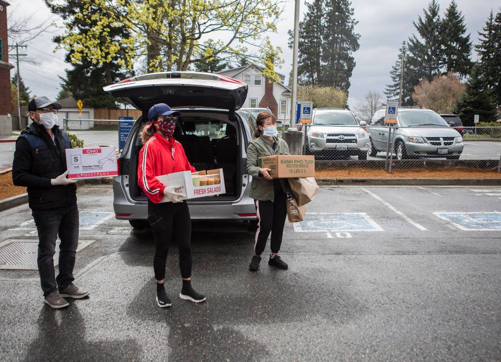 From left, Khoa Bach, Nga Nguyen and Cindy Nguyen wait to deliver food at Providence Regional Medical Center Everett on Saturday. (Olivia Vanni / The Herald)
