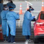 Health care workers test for the coronavirus at a drive-through testing site in a parking lot near Everett Memorial Stadium, March 23, 2020 in Everett. Federal support for the testing site, which first opened on March 23, is being pulled, which could jeopardize the service. (Andy Bronson / Herald file photo)