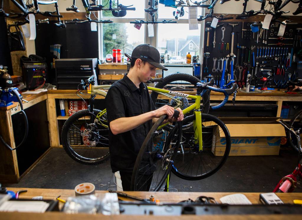 Bicycle Centres of Snohomish mechanic Tanner Wooden grabs a bike that was dropped off for repair on Saturday in Snohomish. (Olivia Vanni / The Herald)