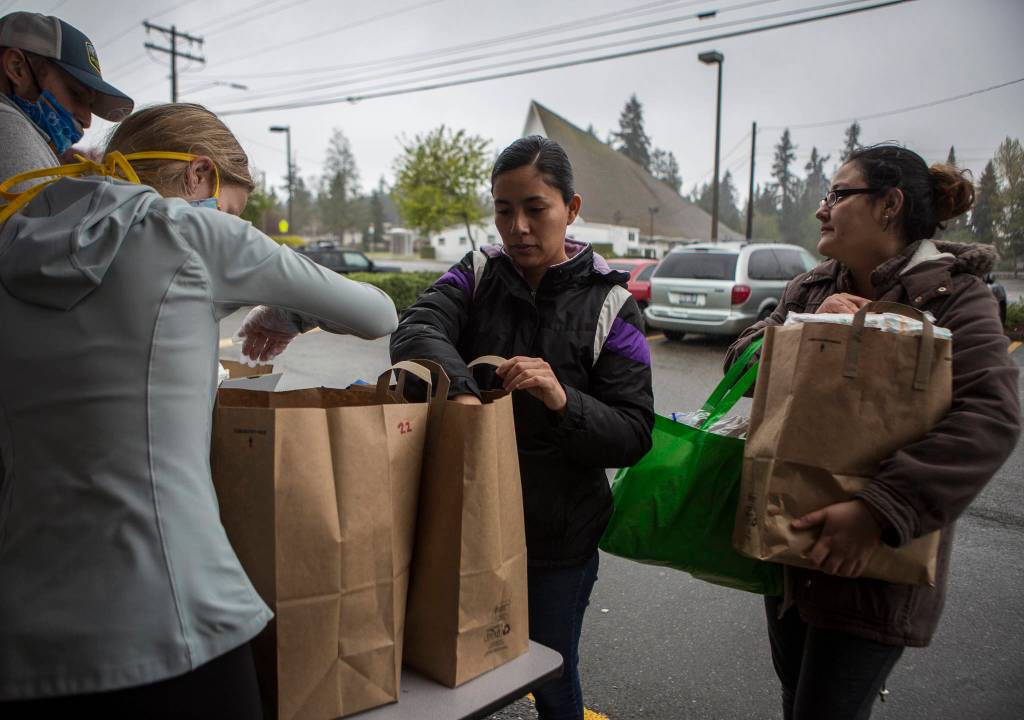 Yasmin (center) and Nancy (right) receive food at The Village in Everett on April 21. (Olivia Vanni / The Herald)