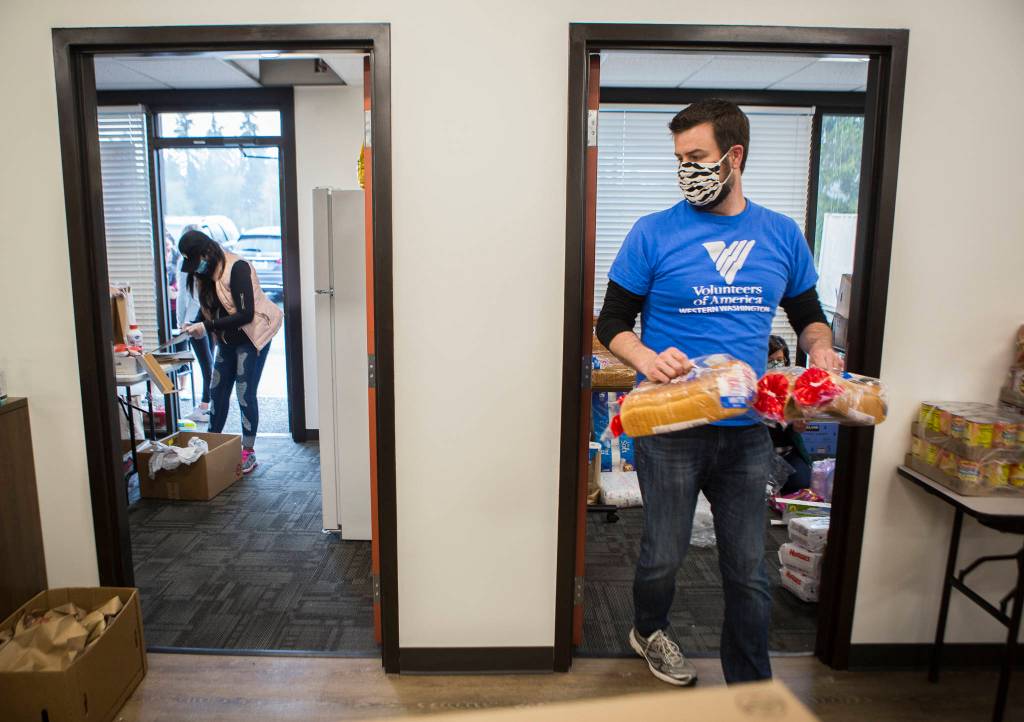 David Jordan helps restock bread April 21 at The Village in Everett. (Olivia Vanni / The Herald)