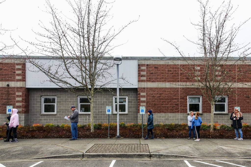 Parents and students wait outside Henry M. Jackson High School in Mill Creek in check out devices on March 18. (Kevin Clark / Herald file)