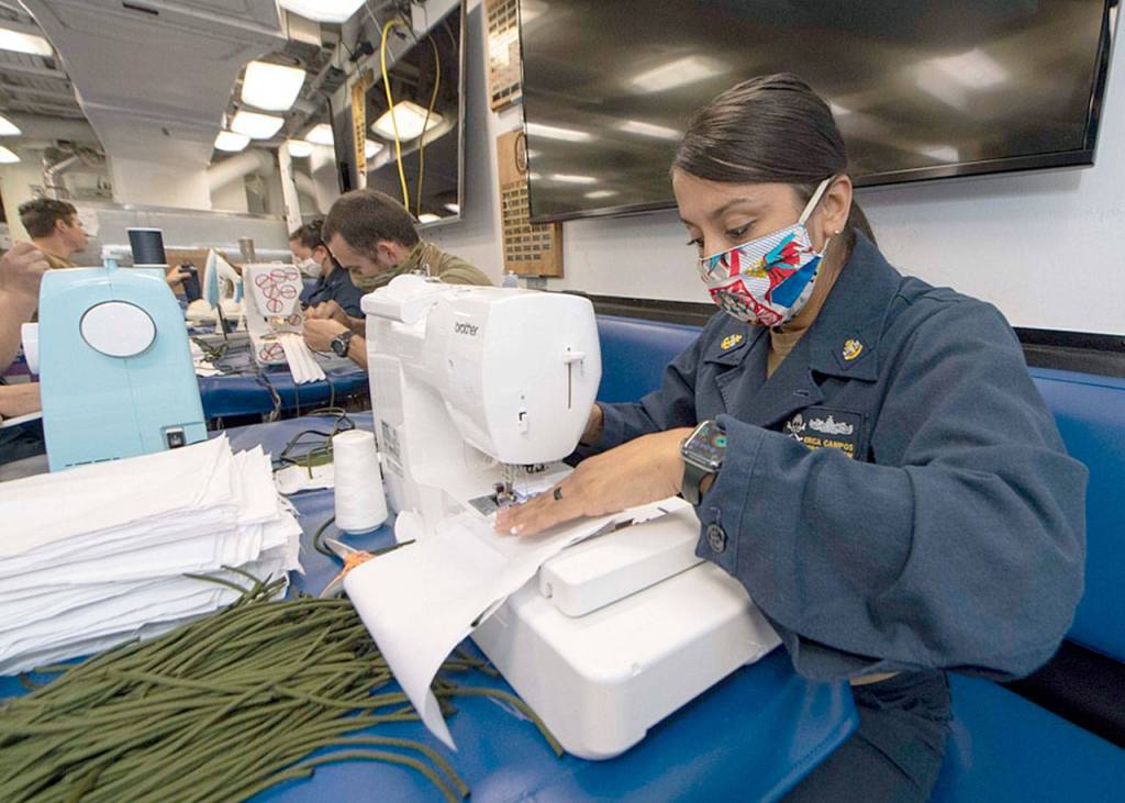 Chief Personnel Specialist Erica Campos, from Houston, assigned to the Everett-based guided-missile destroyer USS Kidd, sews fabric to make cloth face masks for the crew earlier this month while at sea. (Mass Communication Specialist 3rd Class Brandie Nuzzi / U.S. Navy)
